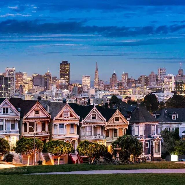 Le famose Painted女士 di Alamo Square sono raffigurate davanti allo skyline di 贝博体彩app al crepuscolo.